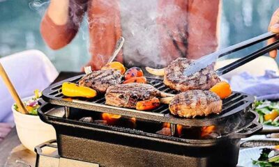 Close-up of a Lodge Sportsman Grill with sizzling food on the cast iron grate.