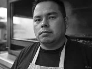 Black-and-white portrait of Diego 'El Fuego' Morales, grill master cooking with bold Latin flavors in San Antonio, Texas