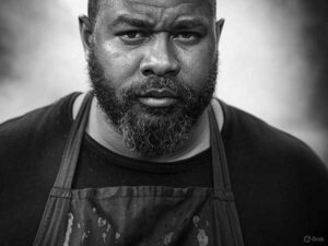 Black-and-white portrait of Travis 'Smoke Daddy' Wheeler, BBQ expert smoking brisket in Franklin, Tennessee