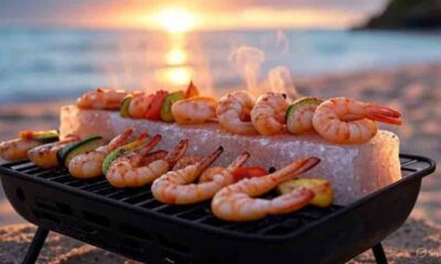 Grilling shrimp and vegetables on a Himalayan salt block at a beachside BBQ with sunset glow