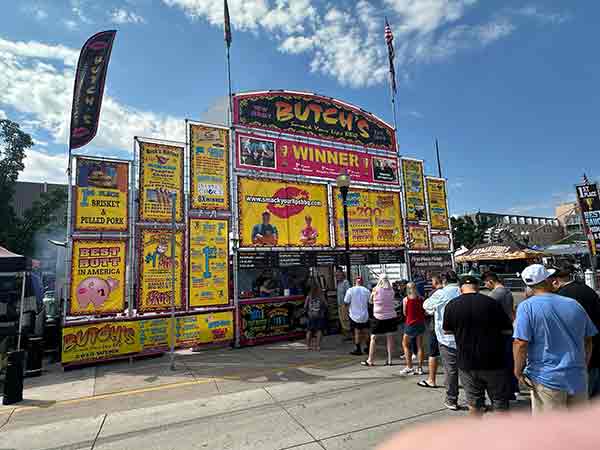 Butch's Smack Your Lips BBQ booth with colorful signs and crowd at 2025 Rib Cook-Off