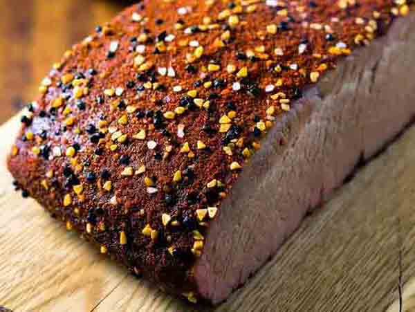 Close-up hero of brisket dry rub-coated meat on cutting board, showcasing coarse spices and glossy surface for perfect bark formation in low-and-slow smoking