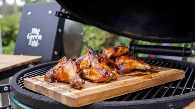 Bourbon maple chicken wings smoking on a Big Green Egg with glossy caramelized glaze and cherry wood smoke