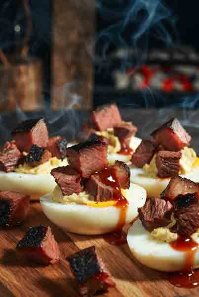 Texas Brisket Smoked Deviled Eggs – Meat Church Style - Popular BBQ Chopped brisket smoked deviled eggs with burnt ends and BBQ sauce drizzle