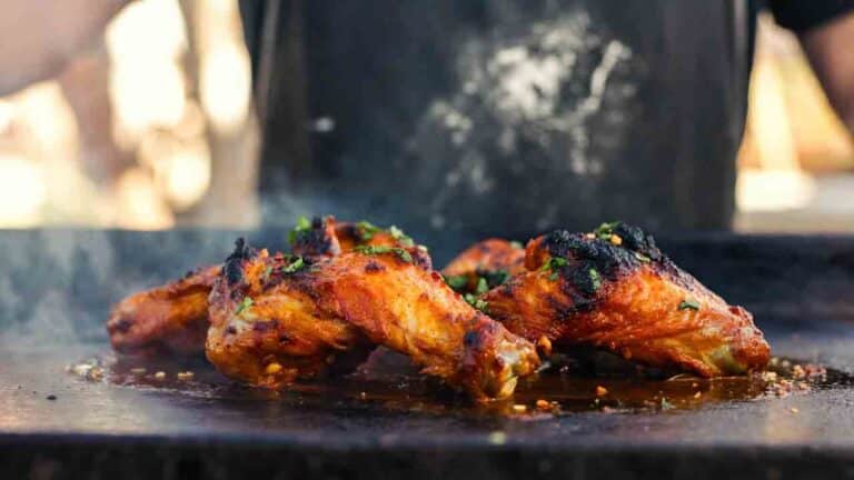 Crispy smoky red chicken wings with guajillo chile char on a hot plancha, garnished with lime and cilantro in a sun-baked El Paso outdoor setting