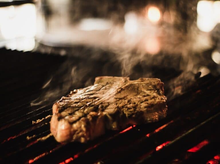 Steak with sear marks on a hot grill — Weber Smokefire vs. Traeger Ironwood searing showdown
