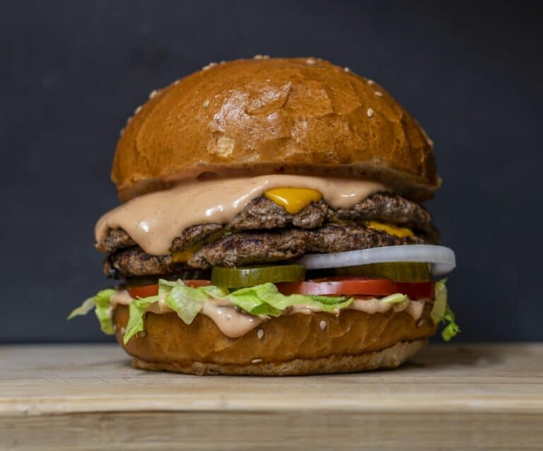 Premium American Wagyu burger patties cooking on a hot grill with visible marbling