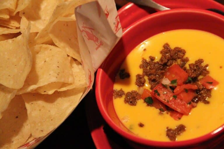 A bowl of smoky chile con queso cheese dip with chips — smoked queso