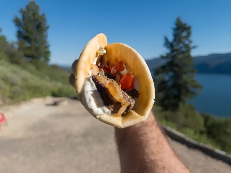 Wild game souvlaki gyro held up on a mountain trail