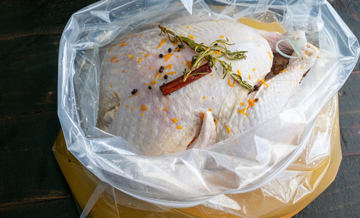 brining-basics-and-techniques Image courtesy of DArtagnan Foods - Popular BBQ Raw turkey seasoned with rosemary, orange zest, peppercorns, and a cinnamon stick in a clear plastic bag on a yellow tray/board